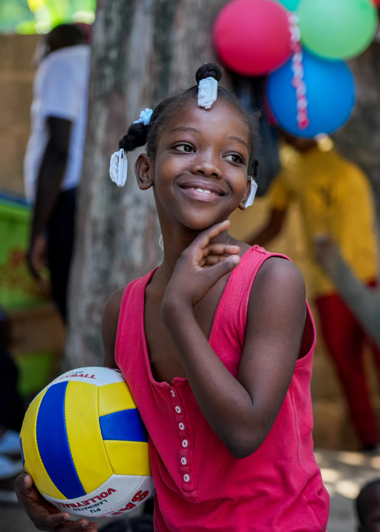 A smiling adolescent girl holds a volleyball at a community event.
