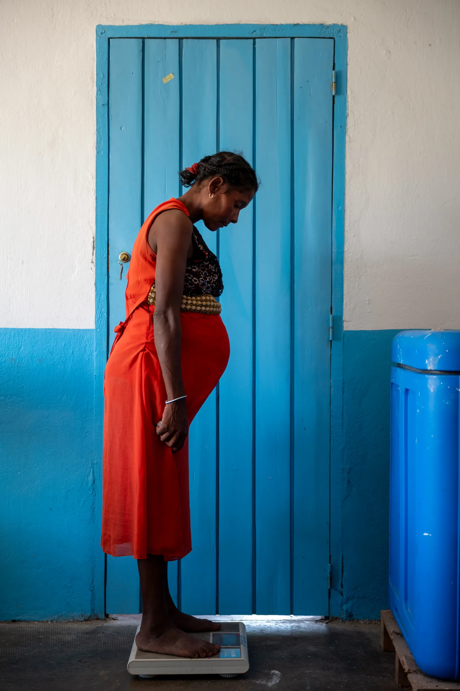 A pregnant woman standing in a doorway at a health centre.