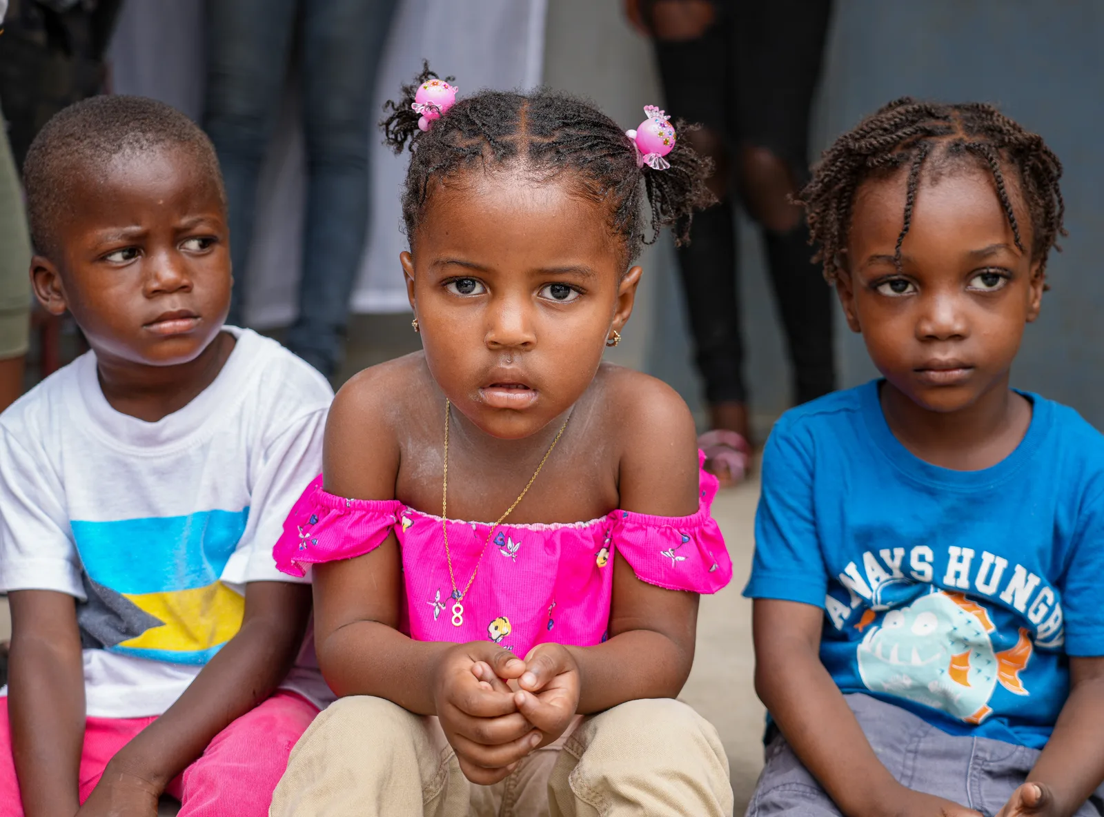 Three young children sitting together, looking towards the camera.