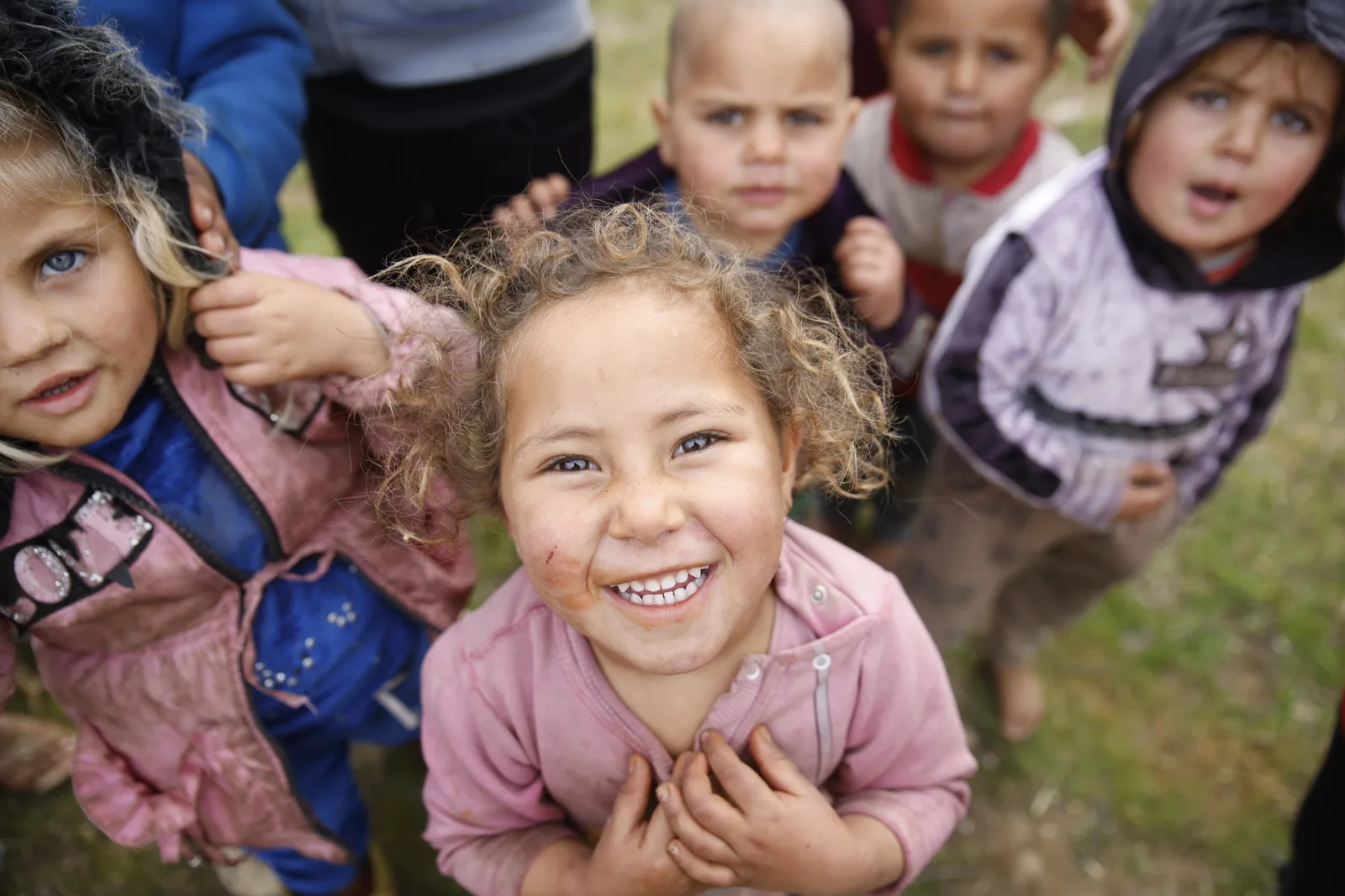 A group of children outdoors, one laughing towards the camera.