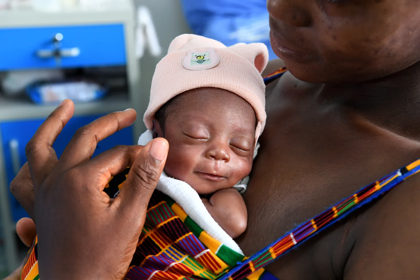 A sleeping newborn held against a parent's chest, skin to skin.