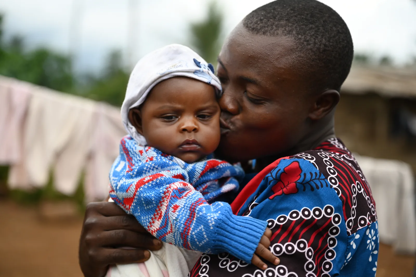 A man holds a baby close to his face, both smiling.