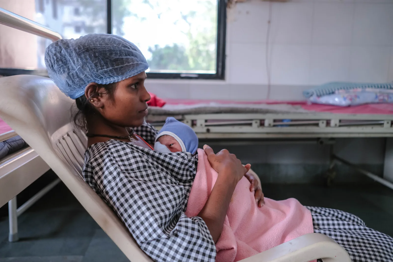 A woman in a hospital bed holding her newborn beside her.